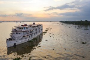 Aerial of boutique river cruise ship The Jahan (Heritage Line) on Mekong river at sunset, Cai Lậy, Tiền Giang, Vietnam